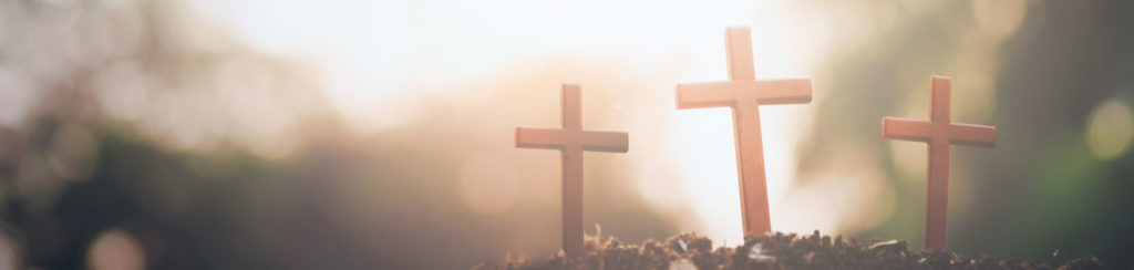 three small wooden crosses in a mound of dirt