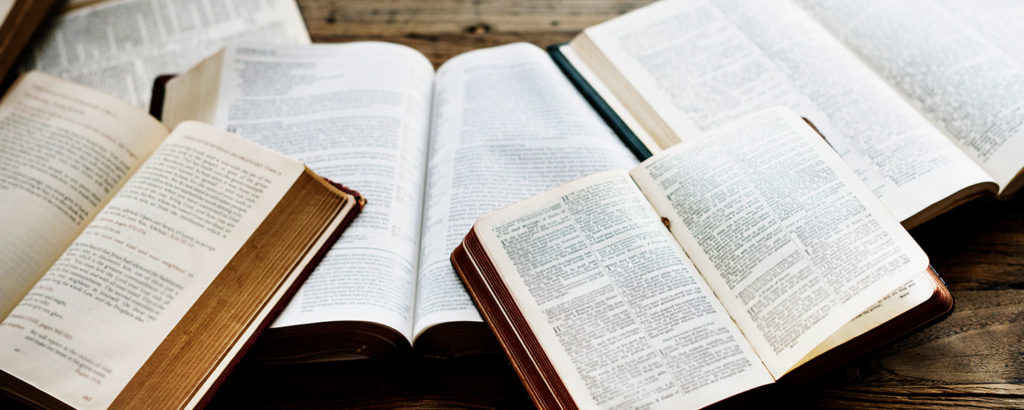 An assortment of bibles laid out on a desk